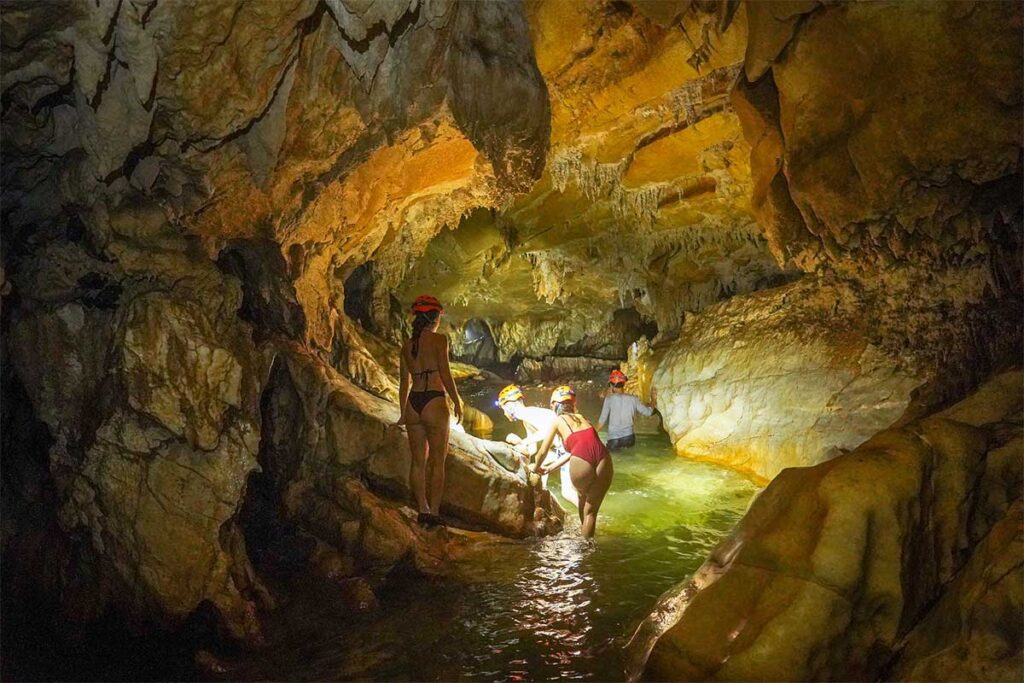 People swimming inside a cave part of a caving tour in Ba Be National Park