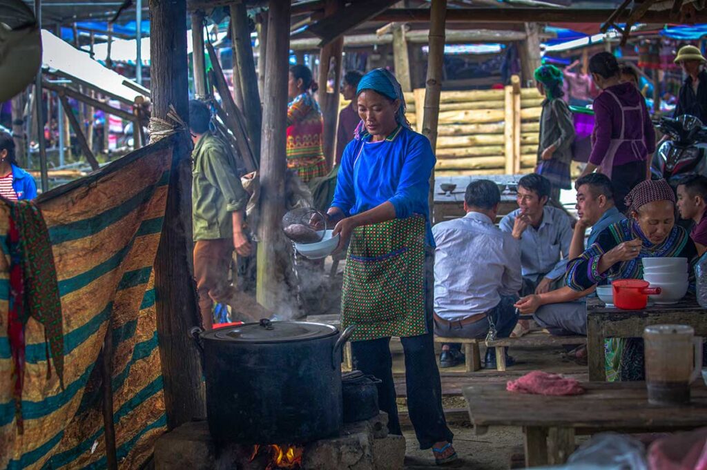 A woman cooking breakfast (soup) at the food area of Bac Ha Market in northern Vietnam