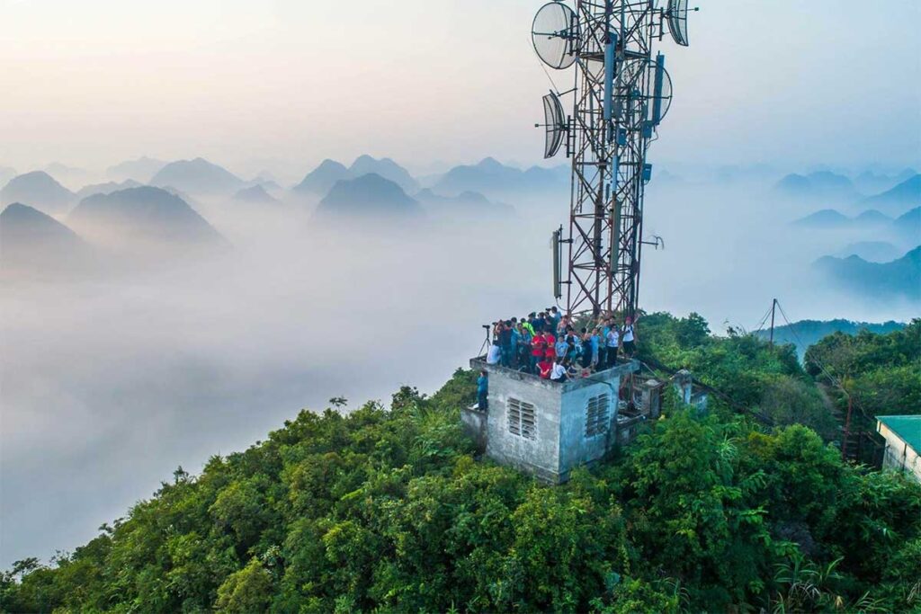 People standing with cameras on the antenna tower on top of Na Lay Peak in Lang Son