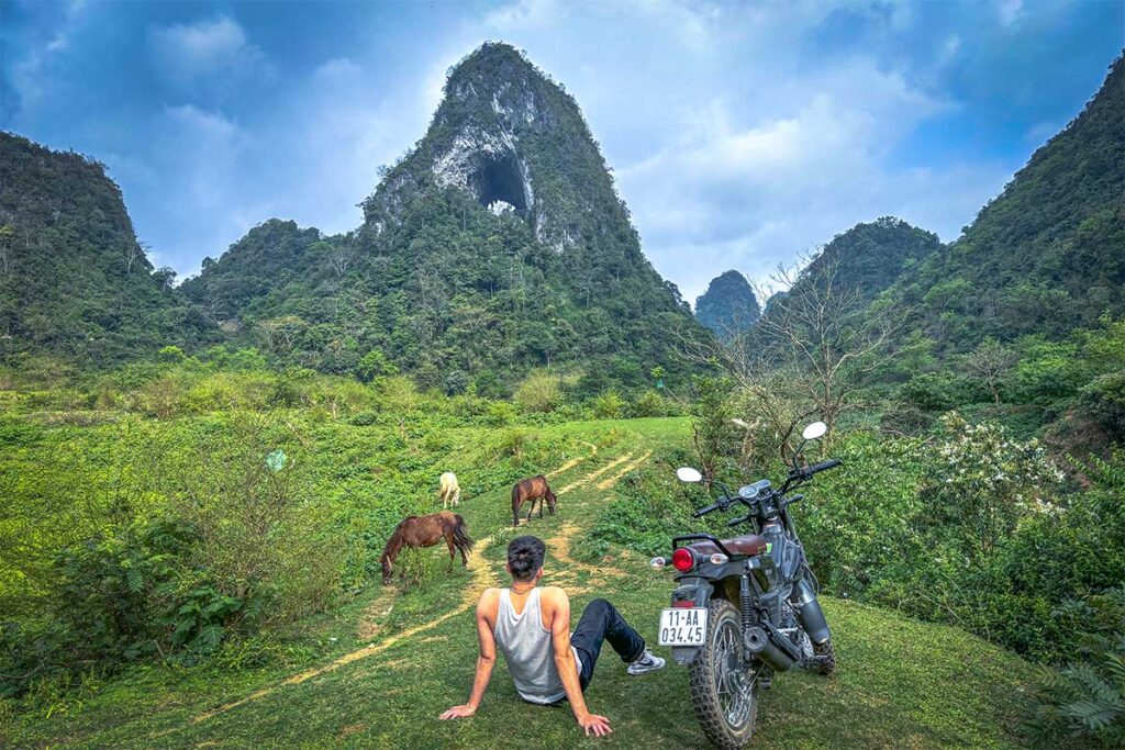 A man sitting next to his rented motorbike at the iconic Angel Eye Mountain in Cao Bang