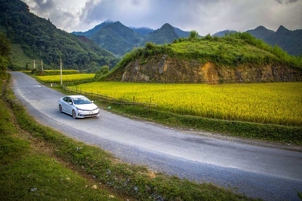 A car driving over the road with scenery of mountains and rice fields of Cao Bang's countryside - Renting car in Cao Bang