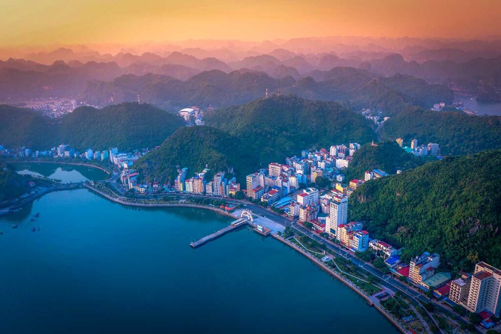 An areal view over Cat Ba Town with ocean in front of the town and stunning mountain scenery behind the town of Cat Ba National Park