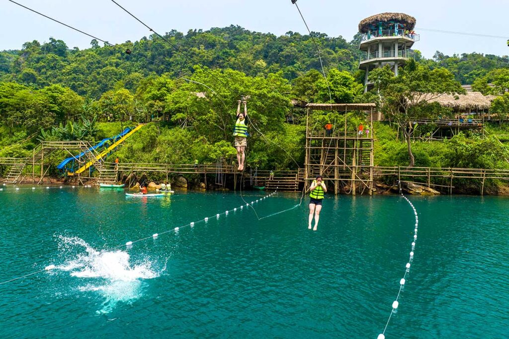 Two people on a zipline dropping themself in the river below at the Dark Cave in Phong Nha