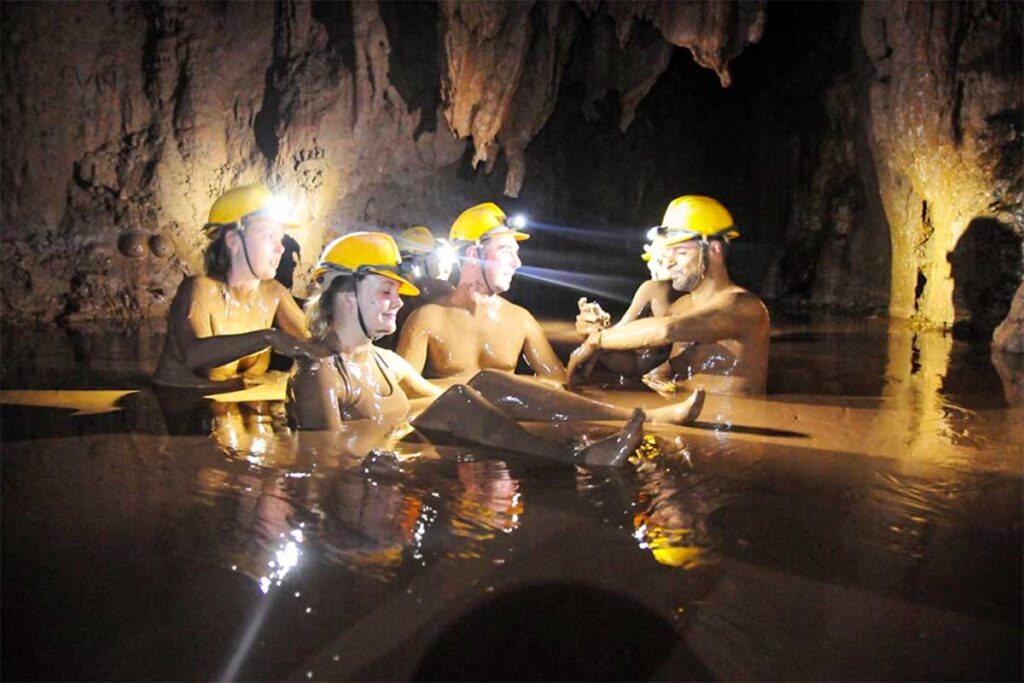 A group of travelers are in a bath full of mud inside the Dark Cave