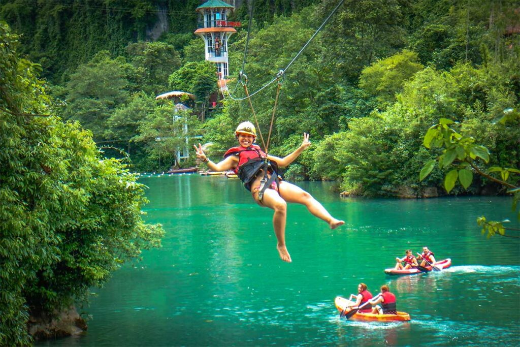 A girl ziplining over a river in Phong Nha to the entrance of Dark Cave