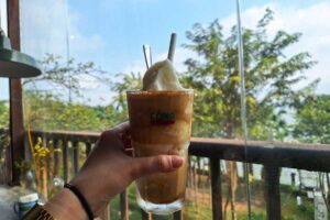 A Vietnamese coconut coffee being held up at a coffee shop in Hanoi