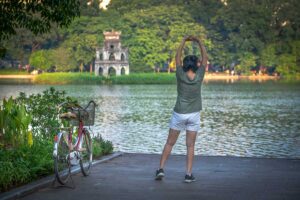 Hanoi n the morning at Hoan Kiem lake - A women stretching herself with bicycle next to her