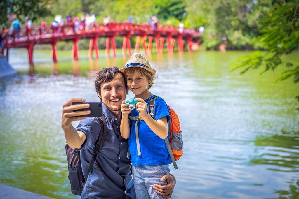 Farther and son taking a picture in Hoan Kiem Lake, a great thing to do with kids in Hanoi