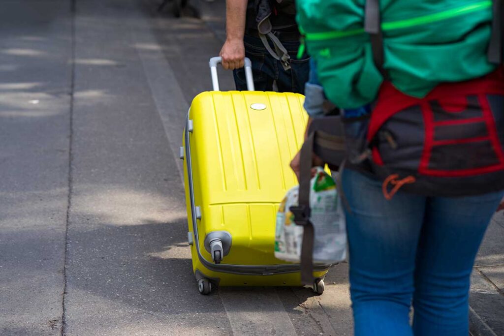 One person dragging a suitcase another person carrying a backpack in Hanoi