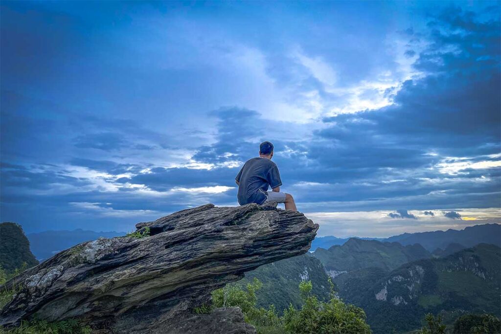 A man sitting on a rock overlooking amazing mountain scenery at Phia Oac National Park in Cao Bang