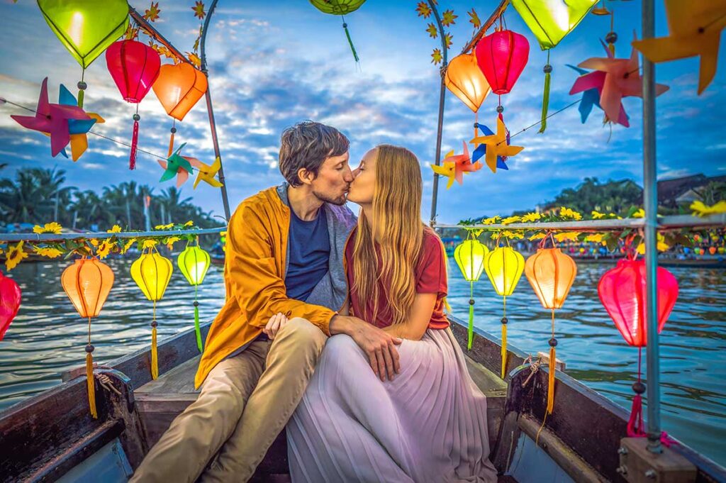 A romantic couple celebrating their honeymoon in Vietnam on a boat tour over the Thon Bon River in Hoi An