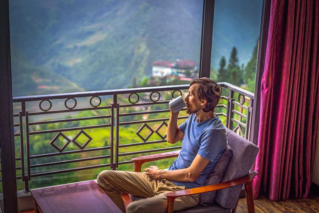 A man drinking inside is hotel room with a view in Sapa