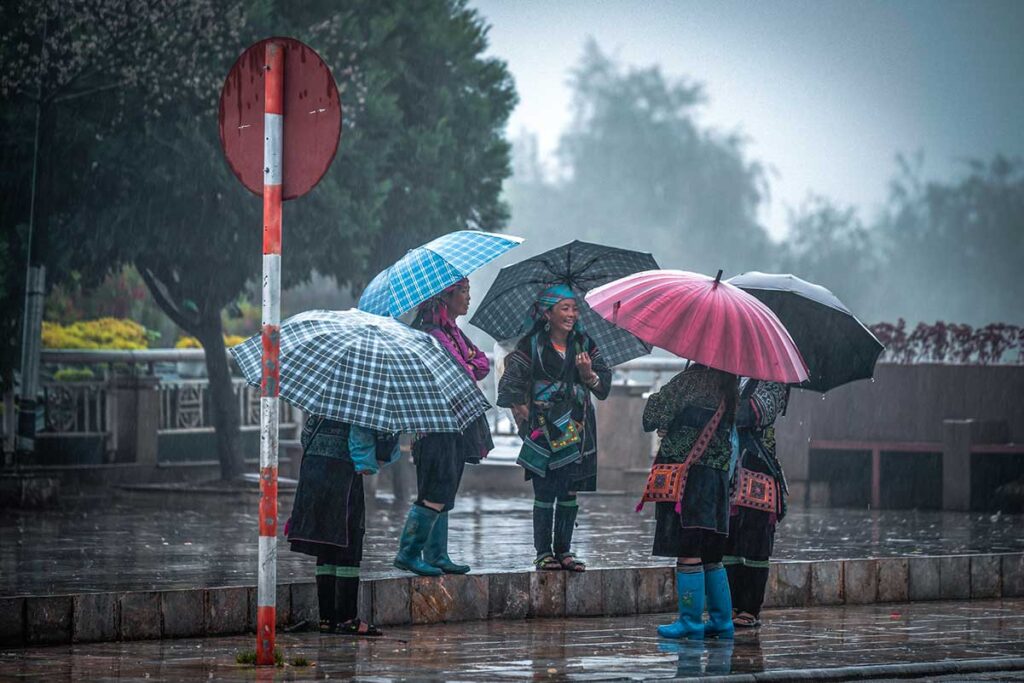 a group of ethnic woman standing with umbrellas in the rain in Sapa