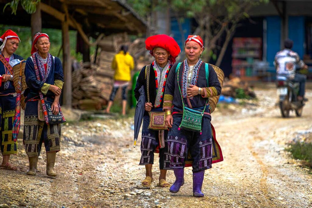 two ethnic Red Dao woman walking through the village of Ta Phin in Muong Hoa Valley near Sapa