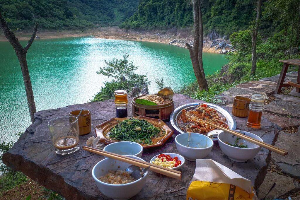 A complete Vietnamese meal on a table right next to Thang Hen Lake