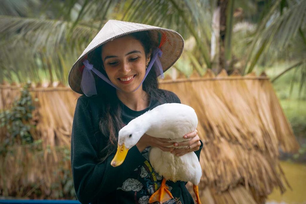 A young tourist woman holding a duck at The Duck Stop in Phong Nha