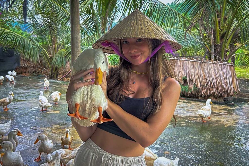 A young tourist girl holding a duck at The Duck Stop in Phong Nha