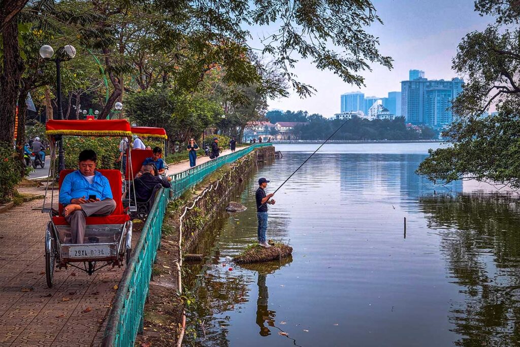 A man sitting in a cyclo parked next to West Lake in Hanoi