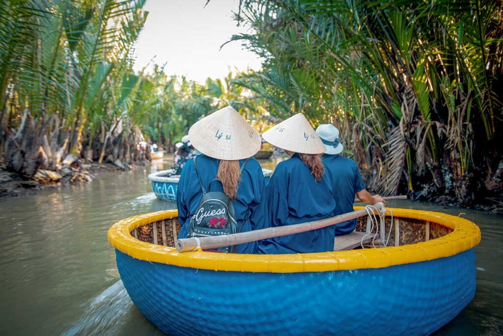 Tourists wearing conical hats on a basket boat ride through Cam Thanh Coconut Village – a fun and unique thing to do in Hoi An.