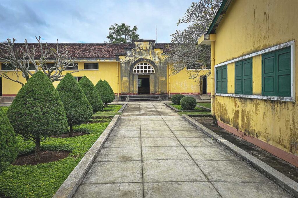 The courtyard of Ban Me Thuot Colonial Prison, with pathways leading to various historical buildings.