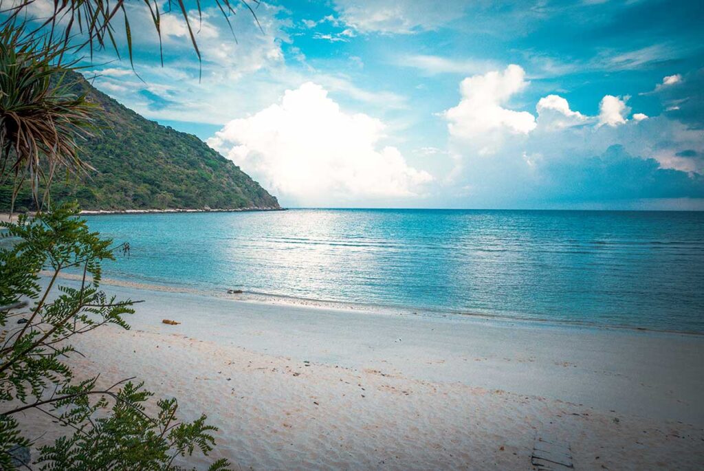 A quiet, empty stretch of Bay Canh Beach in Con Dao, with soft sand and calm waters, perfect for relaxation.