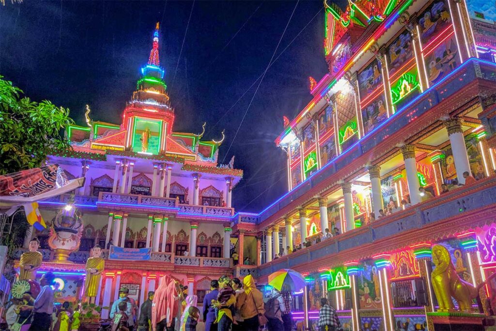 Khmer pagoda festival at Bo Tum Vong Say, Hau Giang, Vietnam – night view with vibrant neon lights and crowds celebrating at the temple.