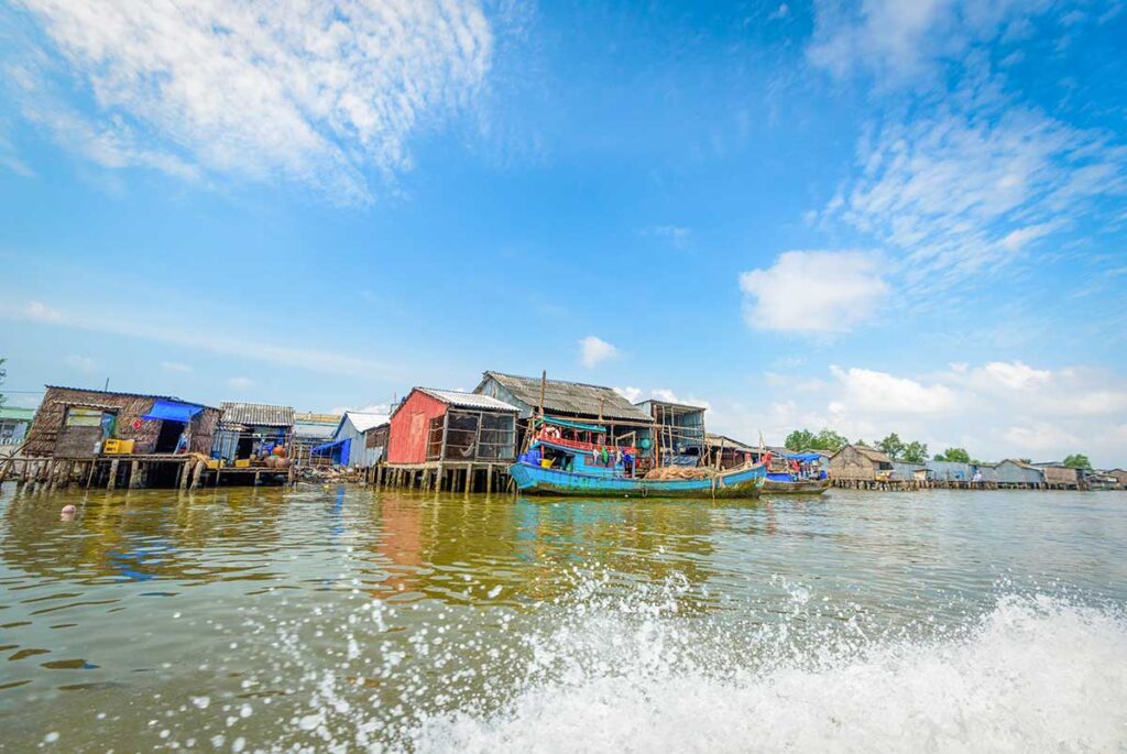 Fishing village in Ca Mau with colorful boats and stilt houses along the river, a typical Mekong Delta scene.