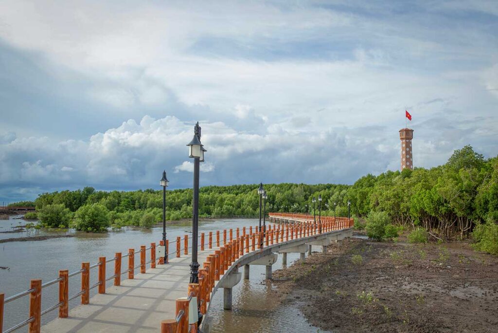 Pathway leading to the Flag Tower at Cape Ca Mau, the southernmost point of Vietnam, with mangrove forests on both sides.