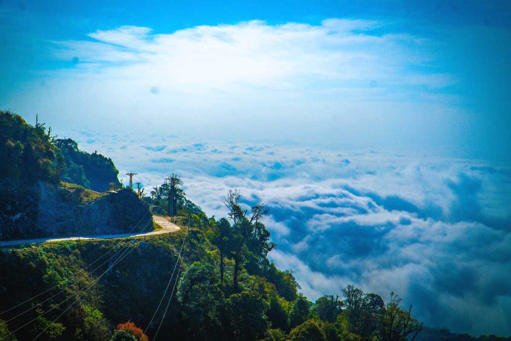 A scenic mountain road at Chieu Lau Thi, with thick clouds rolling below, creating a dramatic cloud-hunting experience in Ha Giang.