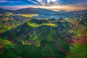 A bird’s-eye view of Chu Dang Ya Volcano, displaying its patchwork of green and brown agricultural fields dotting its slopes.
