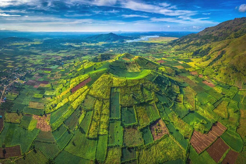 A wide aerial shot capturing the different shades of green and brown fields spread across Chu Dang Ya Volcano.