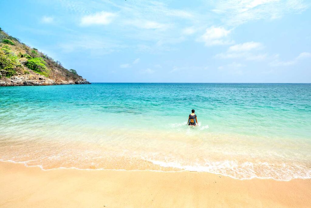 Con Dao in April – A woman enters the crystal-clear ocean for a refreshing swim, enjoying the perfect beach weather of the dry season.