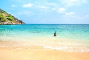 Con Dao in April – A woman enters the crystal-clear ocean for a refreshing swim, enjoying the perfect beach weather of the dry season.