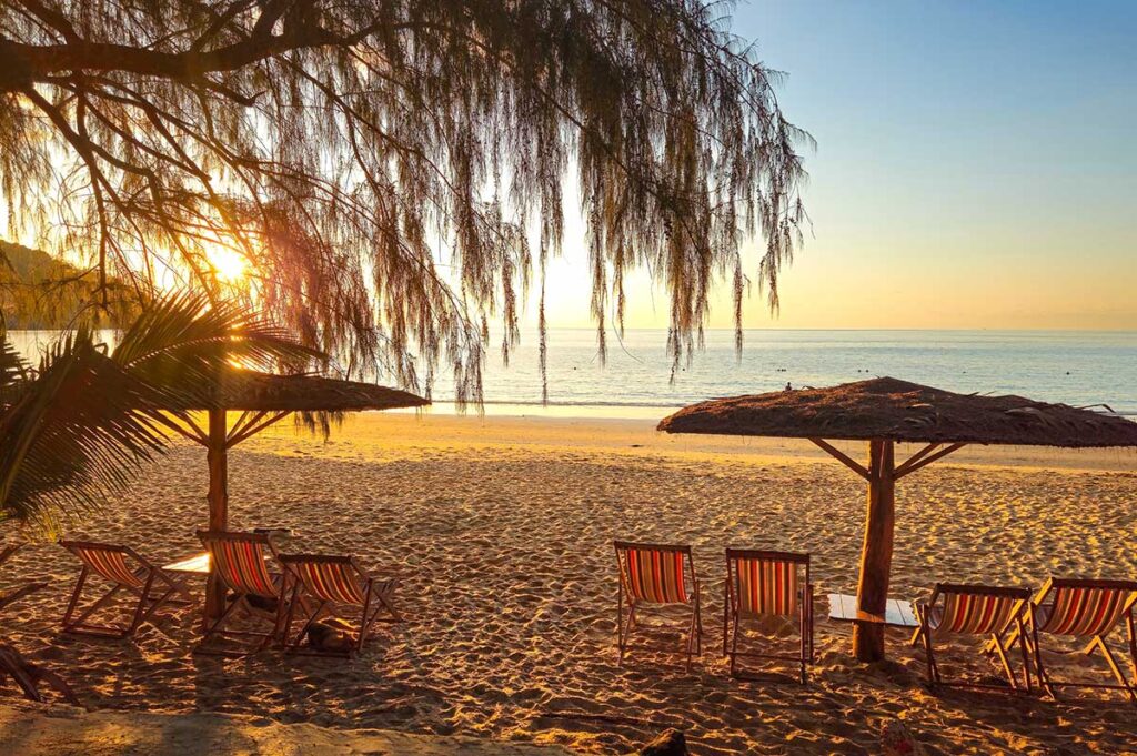 Con Dao in January – A peaceful evening at Dam Trau Beach, with golden sunlight reflecting on the sand and beach chairs facing the calm ocean.