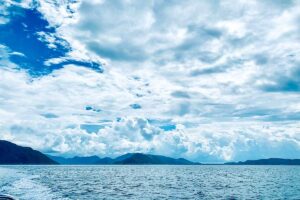 Con Dao in July – A view from the main island towards smaller islands, with thick clouds hanging over the coastline, reflecting the rainy season atmosphere.