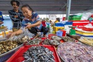 A local woman selling fresh seafood at Con Dao Market, with an array of fish, shellfish, and local specialties on display.