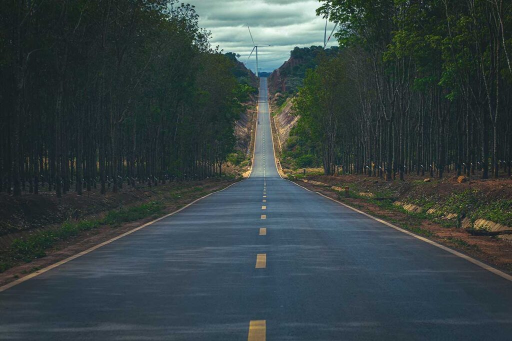 A seemingly endless straight road cutting through the dense forest of Dak Lak, offering a scenic and remote journey.