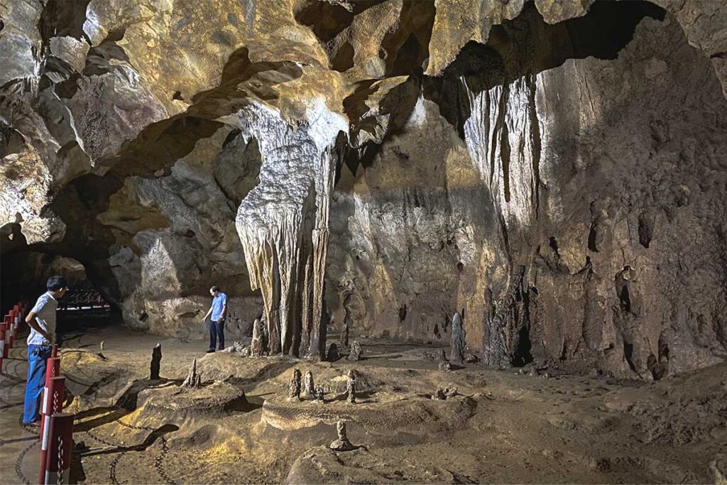 A natural cave in Dien Bien Phu, with two Vietnamese tourists inside, exploring its dark interior.