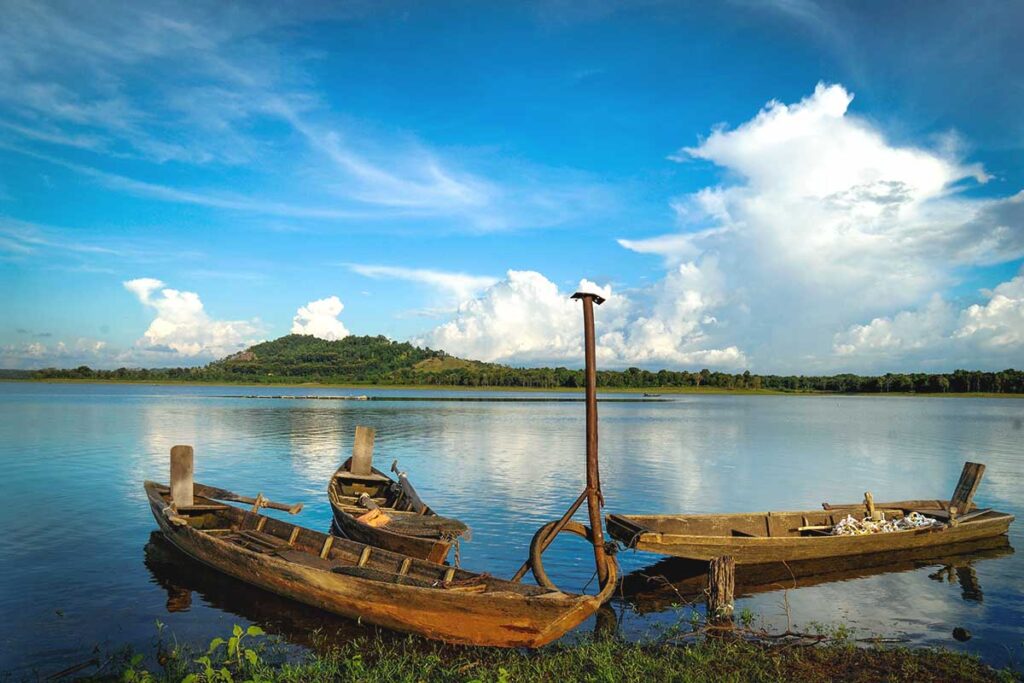 A serene view of Ea Kao Lake in Dak Lak, with three traditional canoes resting on its tranquil shore.