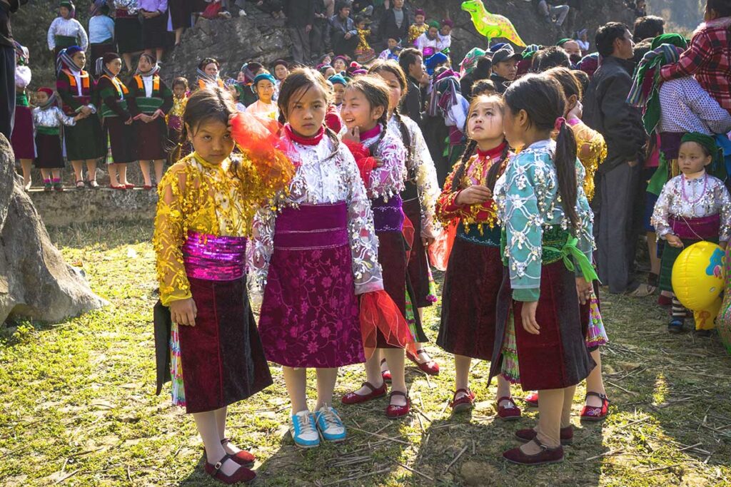 A group of ethnic children dressed in vibrant, shining traditional clothes, celebrating a festival in Ha Giang.