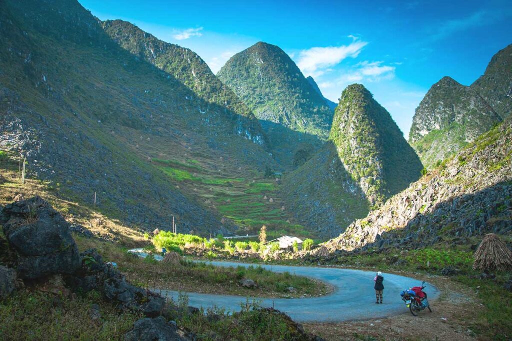 Ha Giang Loop in July – A scenic view of the winding mountain roads near Ma Pi Leng Pass, surrounded by lush green landscapes, capturing the beauty of Ha Giang Loop in July.