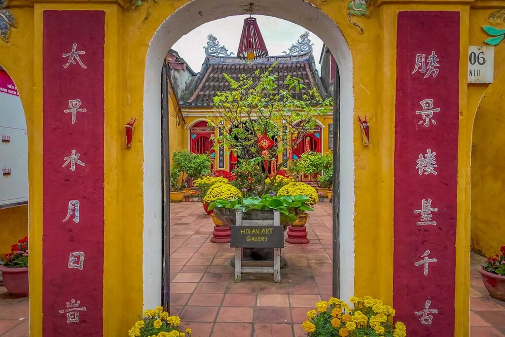 Traditional temple courtyard in Hoi An decorated for Tet Lunar New Year, filled with flowers and festive ornaments celebrating the holiday.