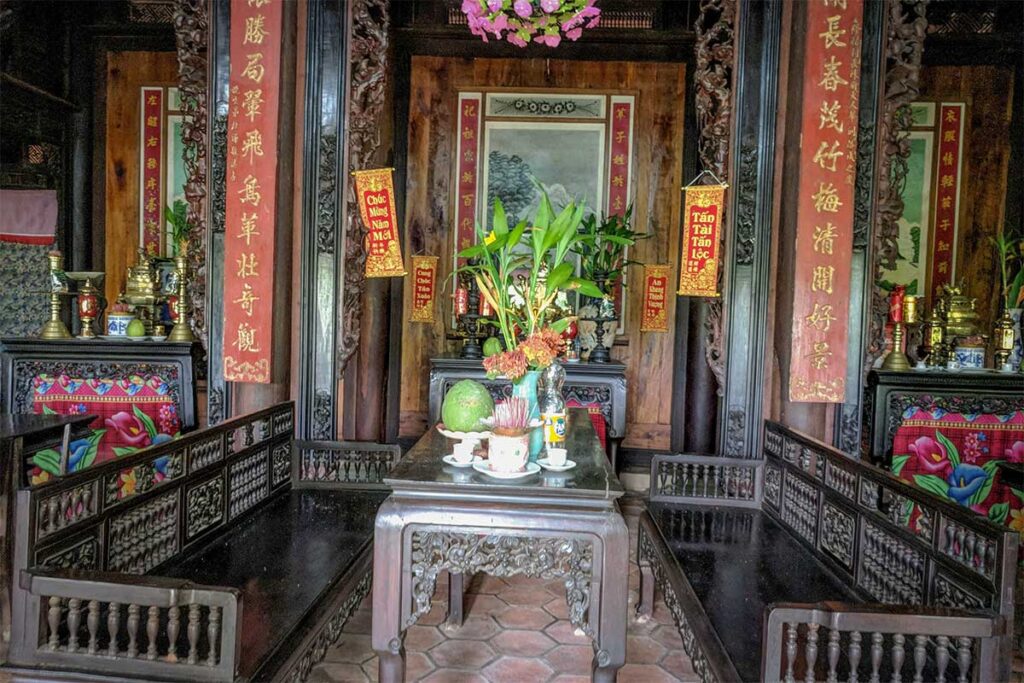 Antique wooden furniture and altars inside the historic Hundred-Column House in Long An, highlighting Vietnamese heritage craftsmanship.