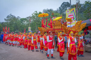 People in colorful traditional temple clothes carrying a golden object in a parade during Hung Kings Temple Festival