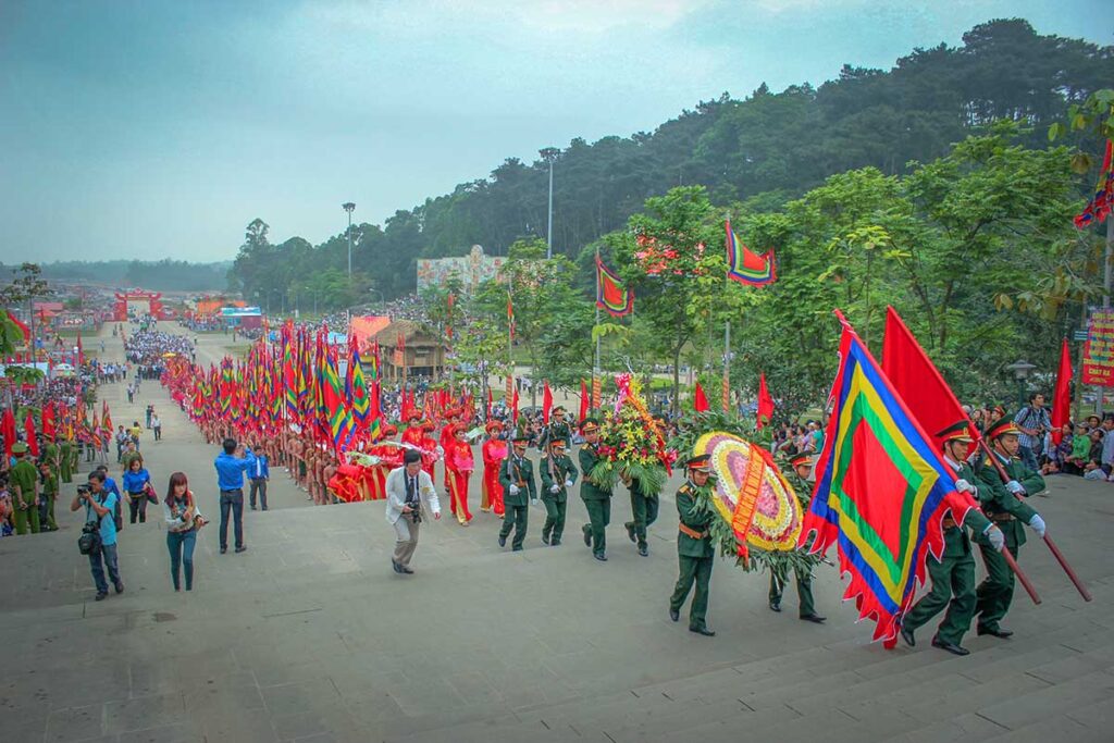 A long parade with flags and people in red traditional temple customs at Hungs King Temple Complex during Hung Kings Festival