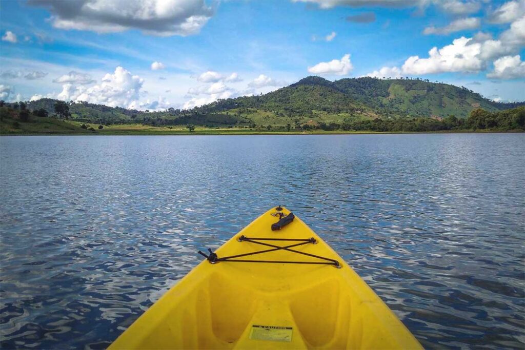 A traveler paddling across the calm waters of Lak Lake, enjoying a peaceful kayaking experience.