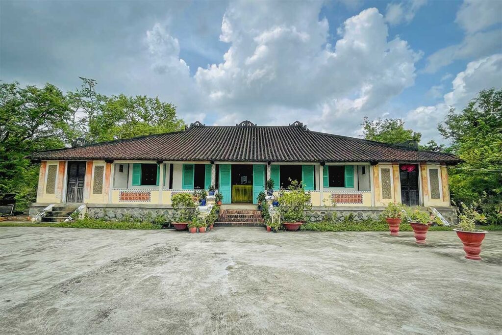 Front view of the Hundred-Column House in Long An, a French-Vietnamese style mansion with turquoise shutters and tile roof.