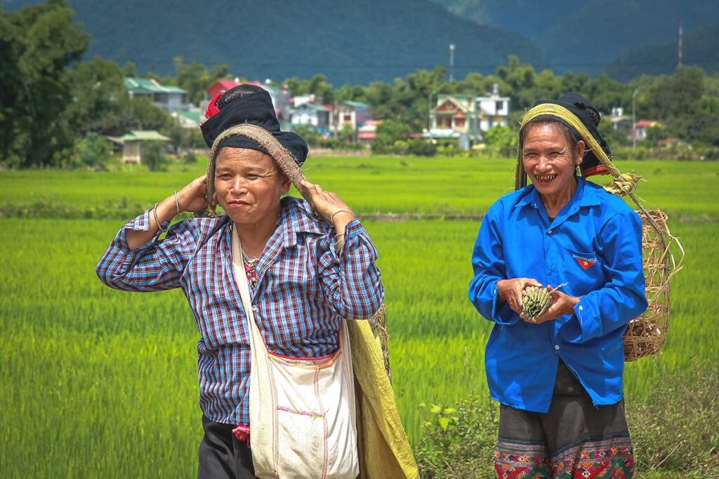 A Lu ethnic minority woman carrying supplies in a traditional basket strapped to her forehead, a common method of transport in the region.