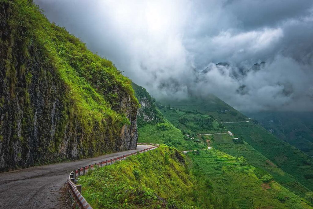 A serpentine road cutting through the towering mountains, highlighting the steep and winding terrain of Ma Pi Leng Pass.