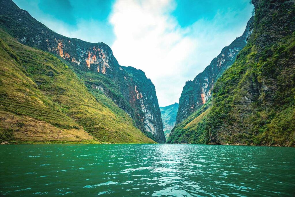 The clear waters of the Nho Que River, framed by towering limestone mountains, offering one of the most scenic views in Ha Giang.